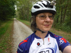 Shari stands on the GAP Trail, showing off the tree-lined view