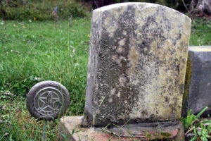 A vertical headstone, but no text on it. With a veterans marker